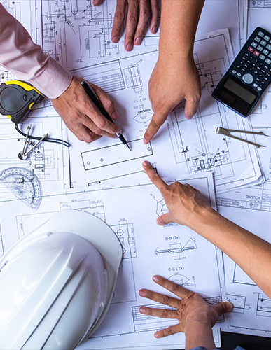 A group of people sitting at a table with construction plans.